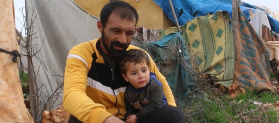 Vater mit Kleinkind in einem Zeltlager in Syrien nach dem Erdbeben