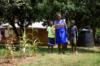 Solaranlagen-Händlerin Sarah Omolo aus Kenia mit zwei ihrer Kinder im Garten