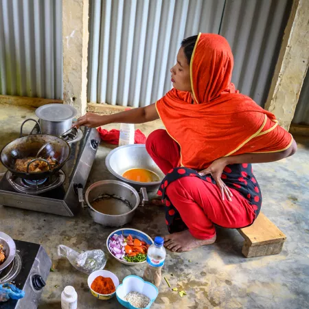 Eine Mutter kocht für ihre Kinder im Flüchtlingslager.