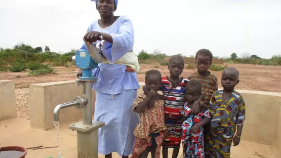 An einem Brunnen holt eine Frau sauberes Wasser