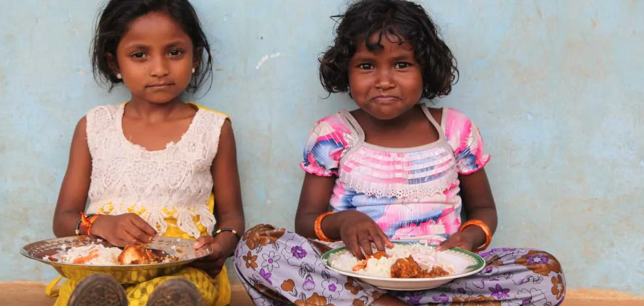 Zwei Mädchen in Indien bei einer Mahlzeit mit Reis