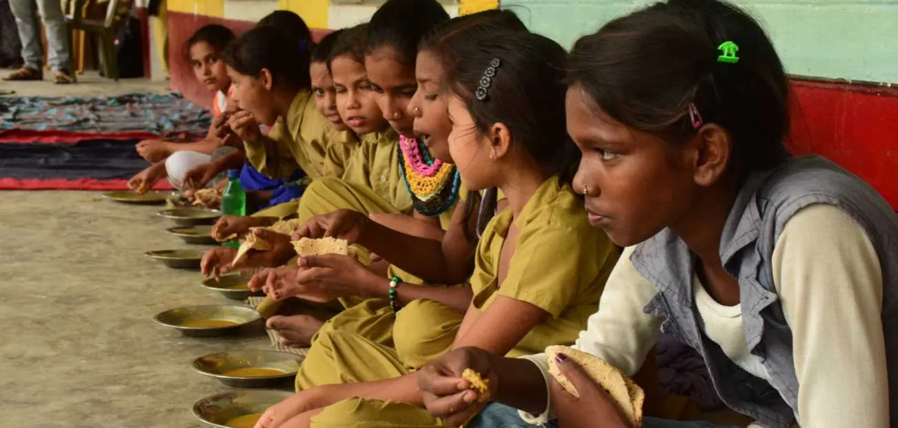 Mädchen in Indien bei einer Schulmahlzeit mit Linsen und Brot