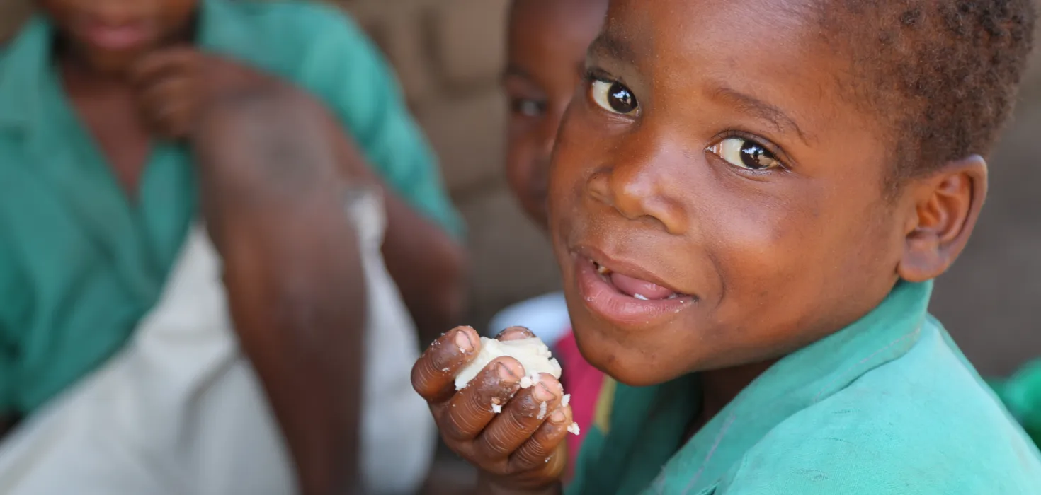 Amos isst etwas von dem Maisbrei Nsami in Malawi.