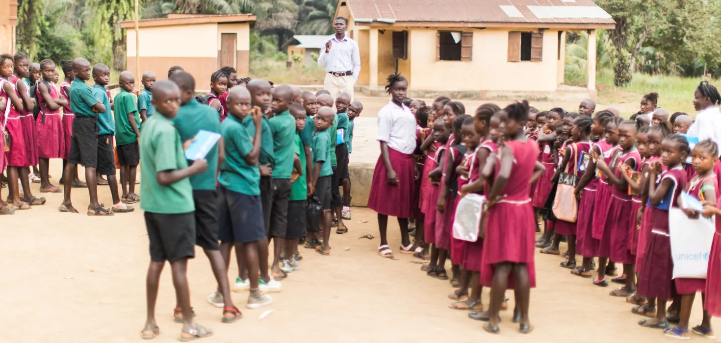 Schulkinder stellen sich vor ihrer Schule in Sierra Leone auf.