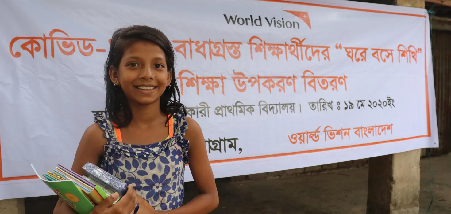 Ein Mädchen nimmt Lernmaterial von World Vision entgegen.