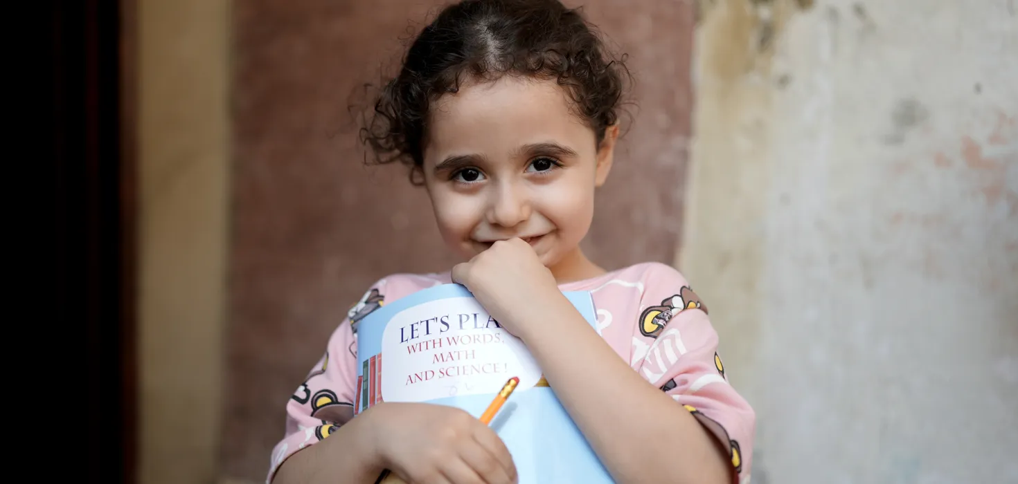 Ein von World Vision unterstütztes Mädchen im Libanon hält ein Mathebuch in den Händen.