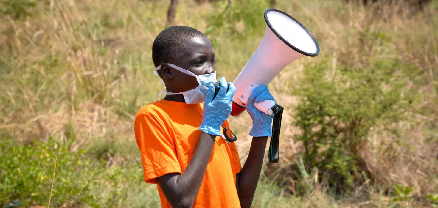 William hilft mit Flüchtlinge in Uganda über das richtige Verhalten in Corona-Zeiten zu informieren.