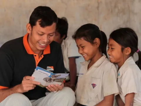 World Vision Mitarbeiter liest zwei Patenkindern in Kambodscha die Post ihrer Paten.