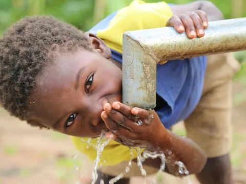 Junge trinkt sauberes Wasser in Malawi