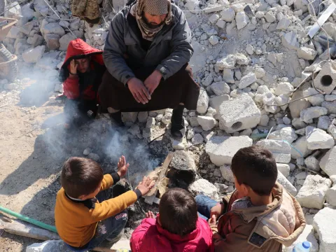 Erdbeben in Syrien: Kinder wärmen sich zwischen Trümmern an einem Feuer.