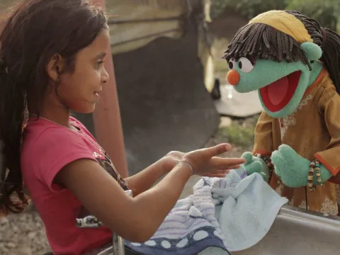 Sesame-Street-Figur Raya übt mit einem syrischen Mädchen das Händewaschen