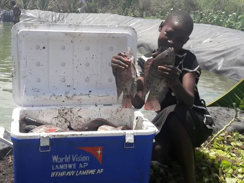 Mädchen zeigt Tilapia aus Fischzucht in Kenia