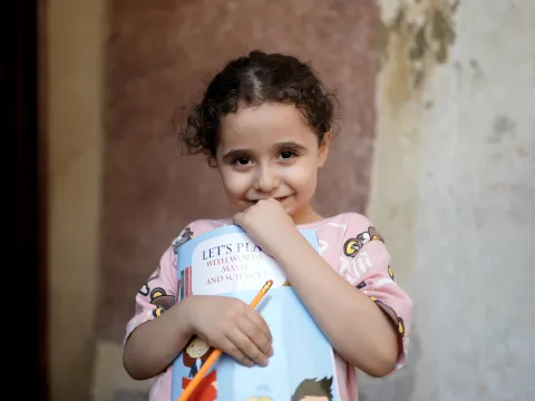 Ein von World Vision unterstütztes Mädchen im Libanon hält ein Mathebuch in den Händen.