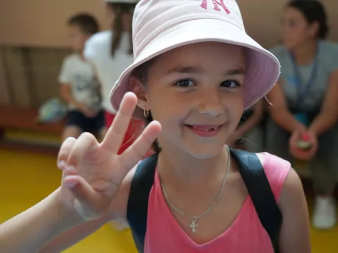Mädchen aus der Ukraine macht Victory-Zeichen in einem Ferien-Camp.