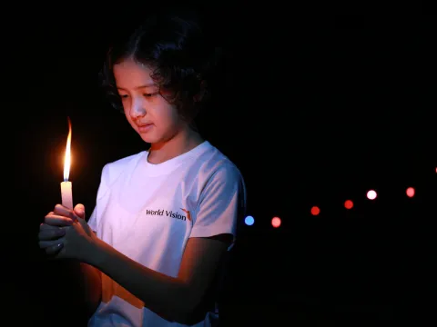 Ein von World Vision unterstütztes Mädchen in Myanmar blickt auf eine brennende Kerze
