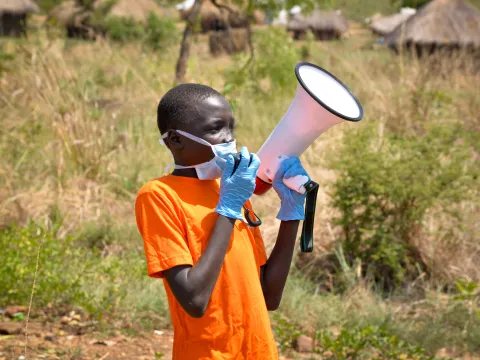 William hilft mit Flüchtlinge in Uganda über das richtige Verhalten in Corona-Zeiten zu informieren.