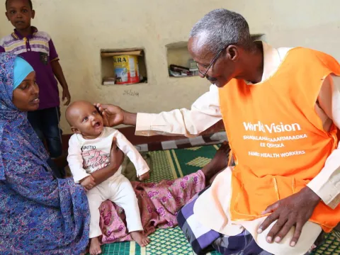 Ein World Vision Mitarbeiter untersucht ein Baby in einer Gesundheitsstation