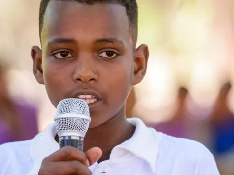 Junge aus Afrika mit Mikrofon in der Hand setzt sich für Kinderrechte ein
