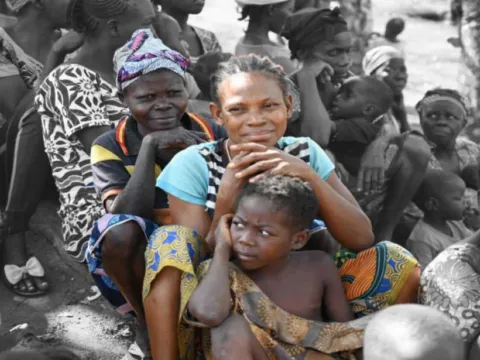 Zwei Frauen und ein Kind mit ihrer Gemeinde in Zentralafrika