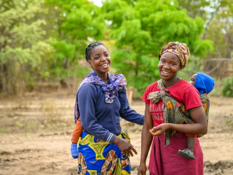 Zwei Frauen aus Afrika mit ihren Kindern lachen gemeinsam