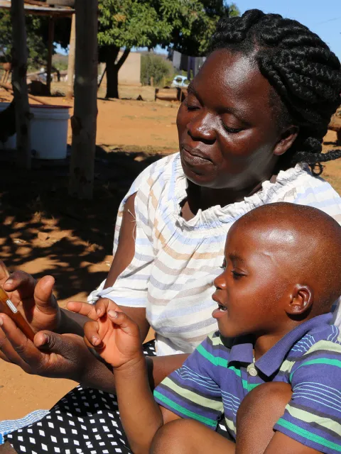 Betty Mhlanga testet mit ihrem Sohn Tamuka in Simbabwe den Audio-Schulunterricht auf dem System VIAMO, unterstützt von World Vision