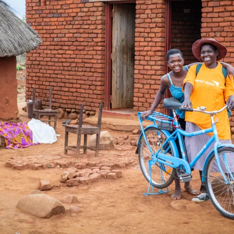 Gertrude aus Simbabwe mit ihrer Tochter und ihremm Fahrrad