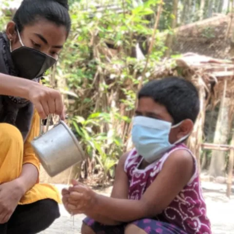 Farzana aus Bangladesch zeigt einem kleineren Kind richtiges Händewaschen.