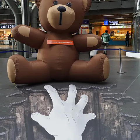 Ein riesiger Teddy steht symbolisch für die bedrohte Kindheit dieser Kinder.