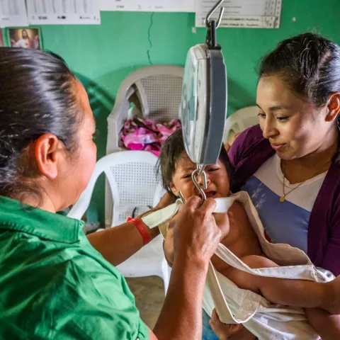 Gesundheitshelferin Carmen aus Honduras wiegt ein kleines Mädchen.