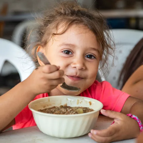Ein Mädchen aus Venezuela freut sich über eine warme Mahlzeit