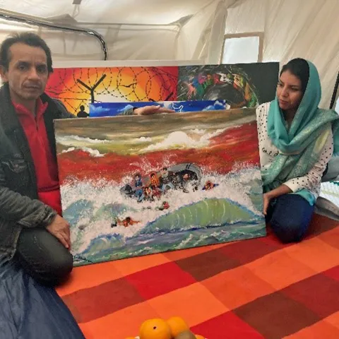 Ein afghanisches Künstler-Ehepaar zeigt ein Bild mit Flüchtlingen in Seenot