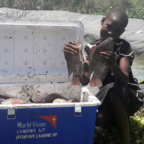 Mädchen zeigt Tilapia aus Fischzucht in Kenia