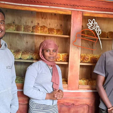 Bona im Verkaufsbereich seiner Bäckerei mit Mitarbeitenden