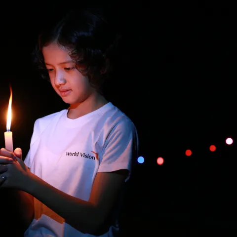 Ein von World Vision unterstütztes Mädchen in Myanmar blickt auf eine brennende Kerze