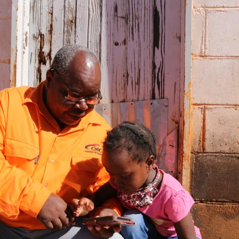 Vater und Tochter testen den Audio-Schulunterricht mit VIAMO in Simbabwe