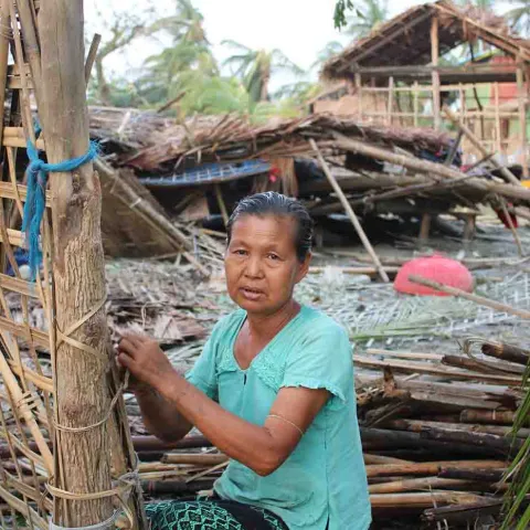 Frau vor ihrem durch einen Wirbelsturm zerstörten Haus in Myanmar