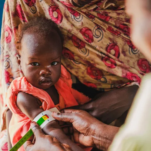 Hebamme Paula Atimango untersucht den Ernährungszustand eines Babies in einer von World Vision betriebenen Nothilfe-Klinik an der Grenze zu Sudan.