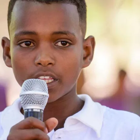 Junge aus Afrika mit Mikrofon in der Hand setzt sich für Kinderrechte ein