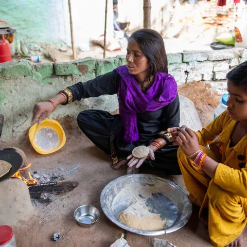 Mutter bereitet mit ihrem Kind Essen zu in Indien