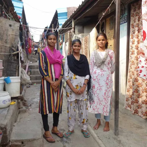 Drei Mädchen in einer Häuserstraße in Indien
