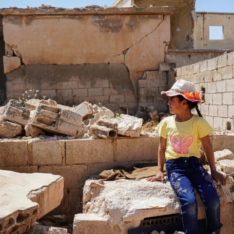 Zwischen den Trümmern seines Elternhause sitzt ein syrisches Mädchen