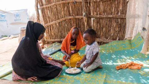 Geflüchtete Kinder aus Sudan teilen sich eine Schulmahlzeit.