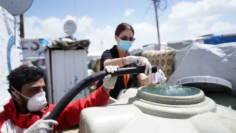 World Vision-Helfer füllen einen Wassertank in einem Flüchtlingslager