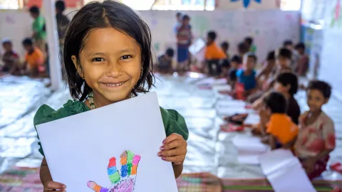 Kind zeigt gemaltes Bild in einem Kinderschutzzentrum