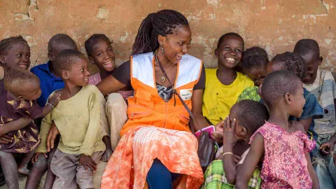 Gemeinsam mit World Vision den Kinder auf der Welt helfen: Mitarbeiterin lacht gemeinsam mit Kindern in Afrika