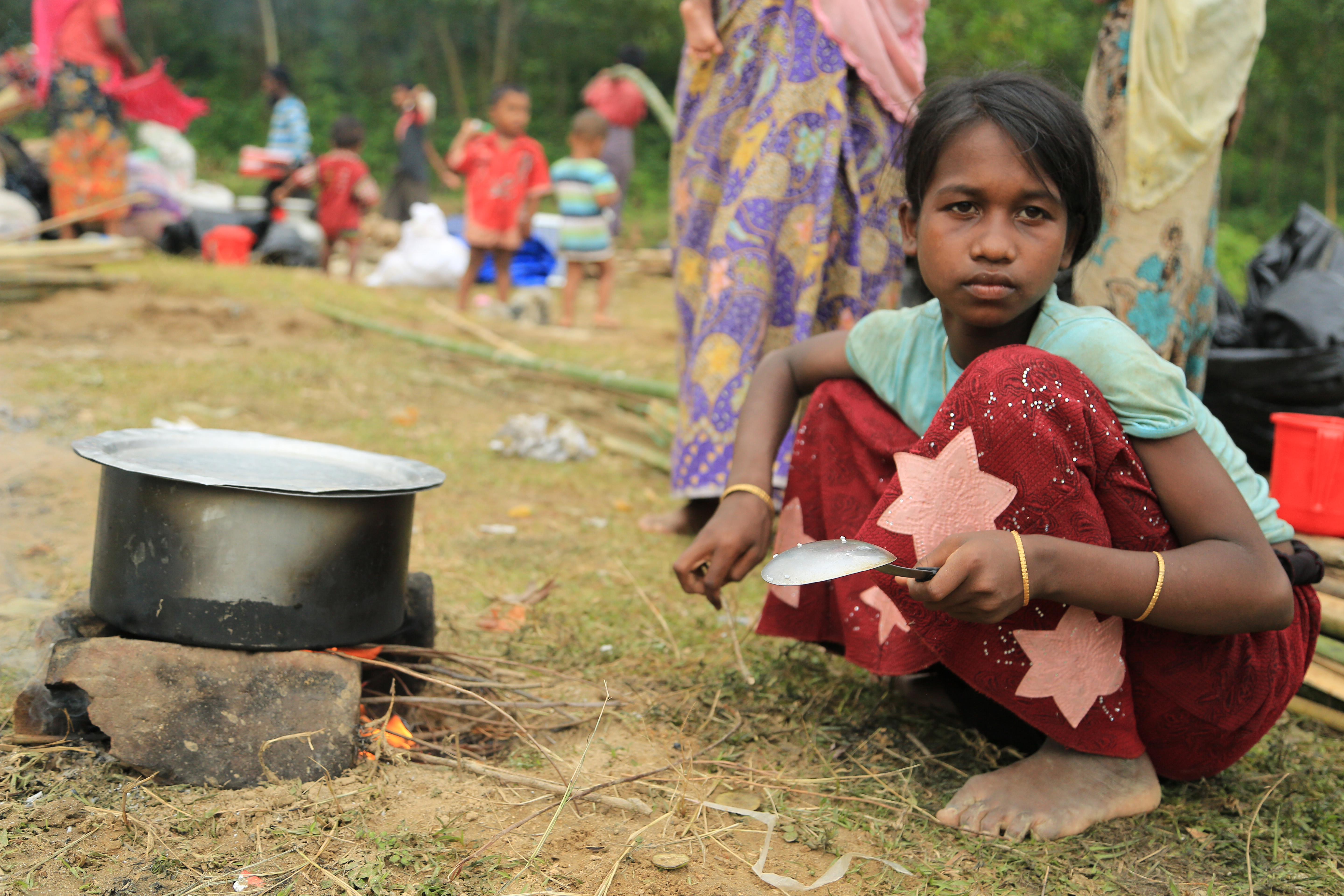 geflüchetes Mädchen aus Myanmar kocht im Freien