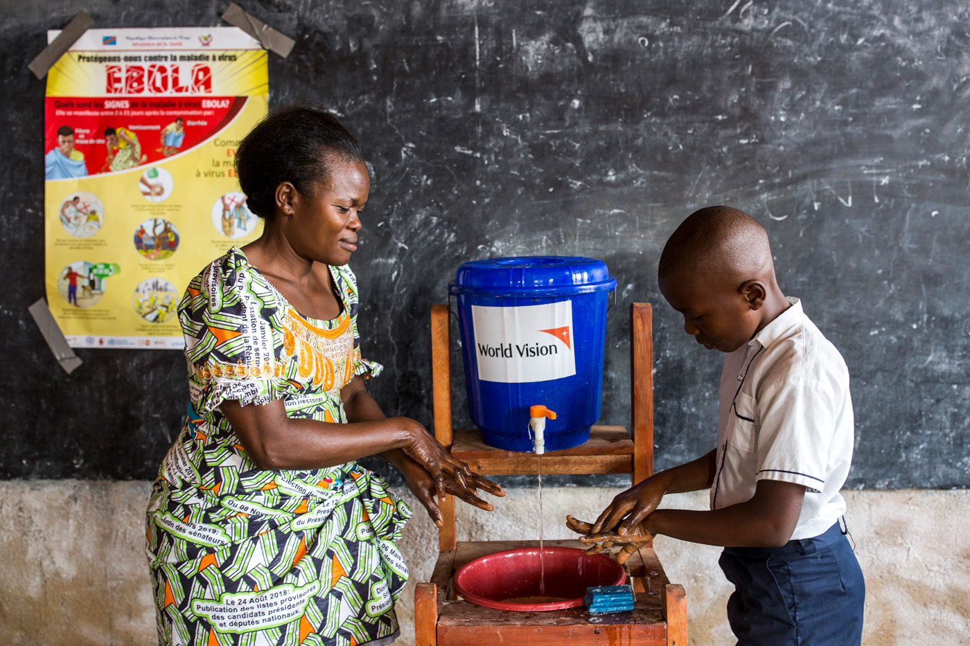 Zusammenarbeit von World Vision mit Schulen im Kampf gegen Ebola im Kongo: eine Lehrerin übt mit Schülern das richtige Händewaschen.
