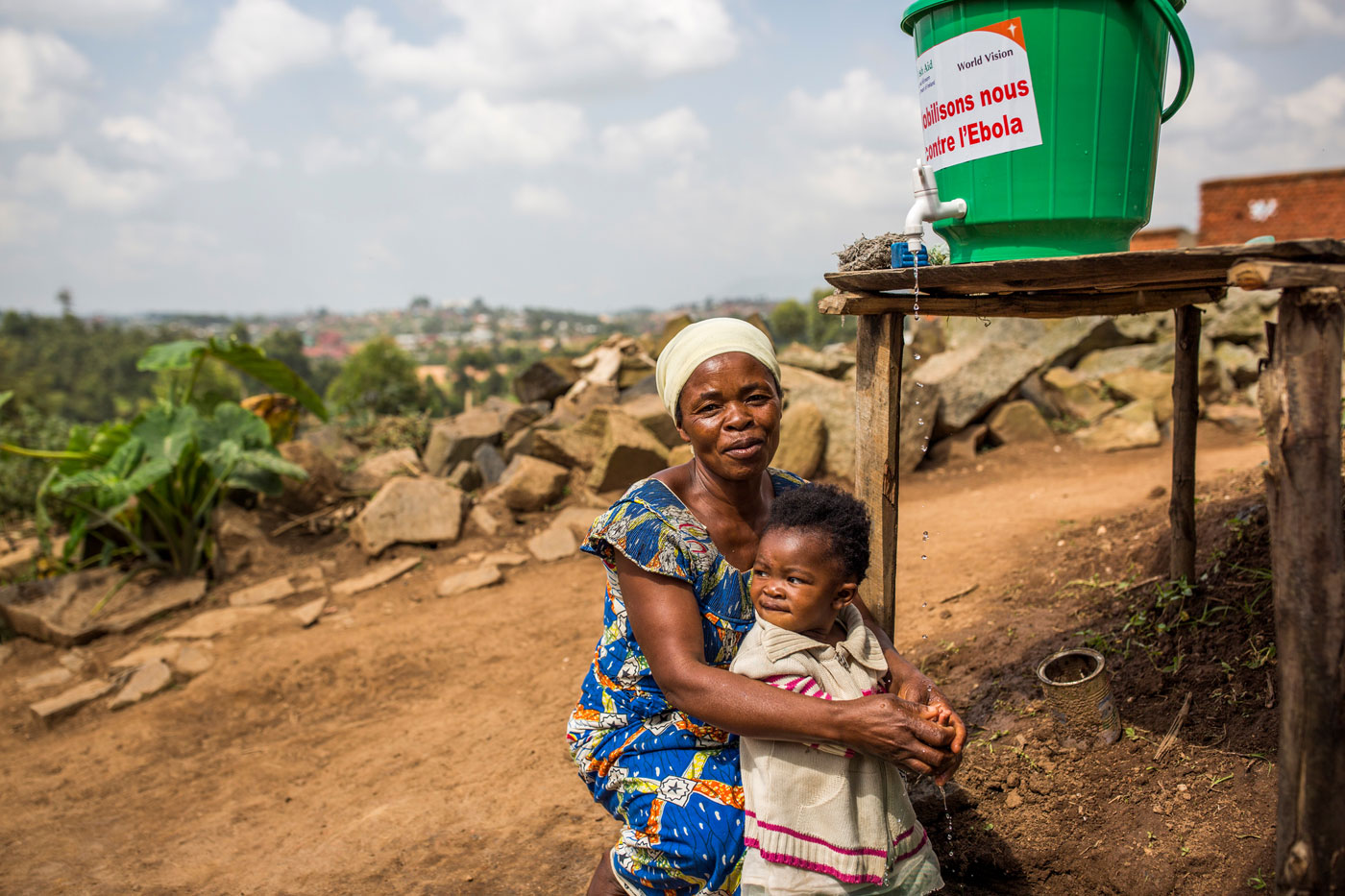 Eine Frau mit Kind vor einer von World Vision installierten Handwaschstation in der Demokratischen Republik Congo
