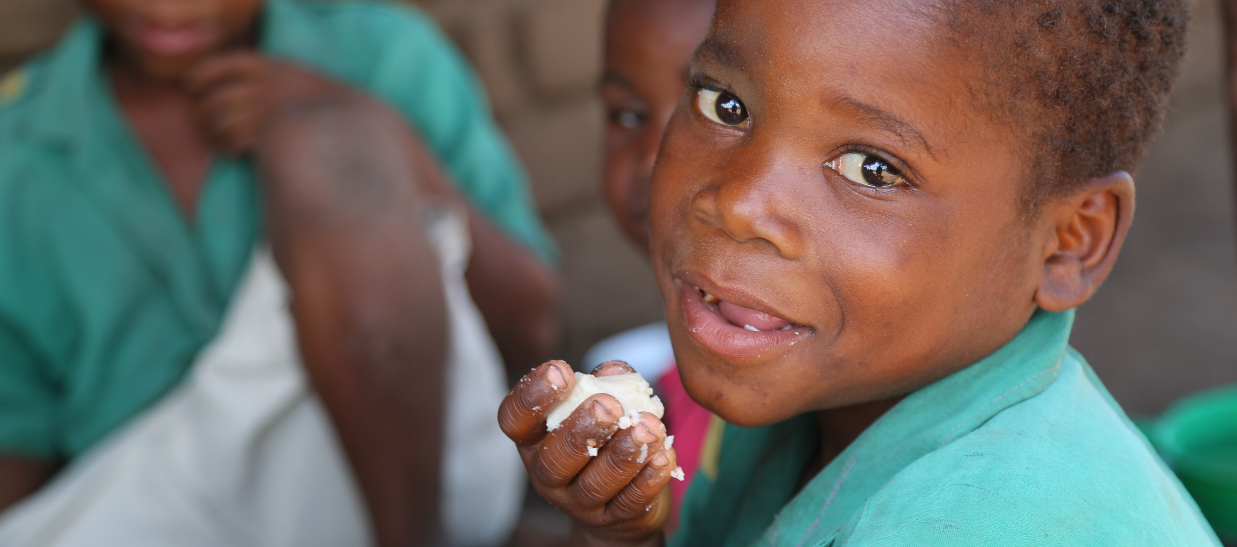 Amos isst etwas von dem Maisbrei Nsami in Malawi.