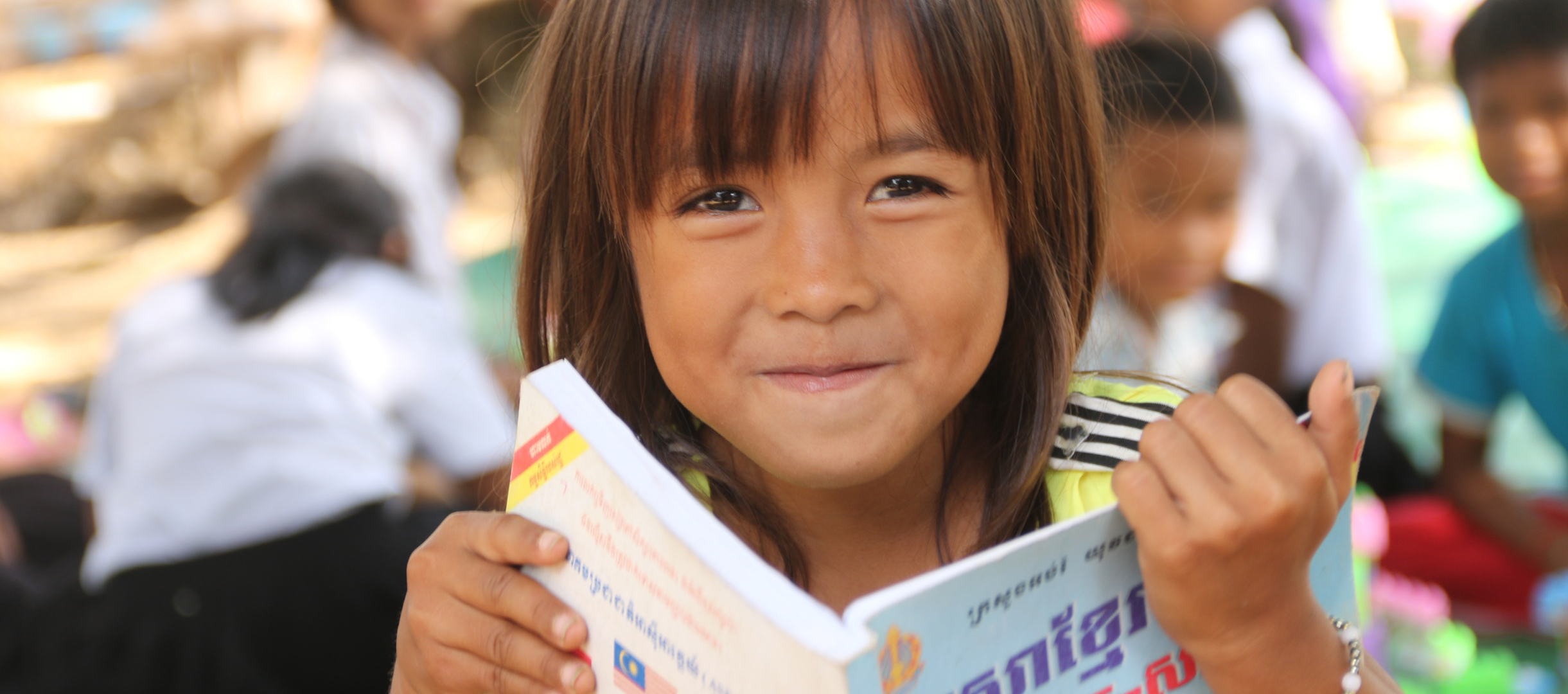 Patenkind aus Kambodscha liest in einem Buch